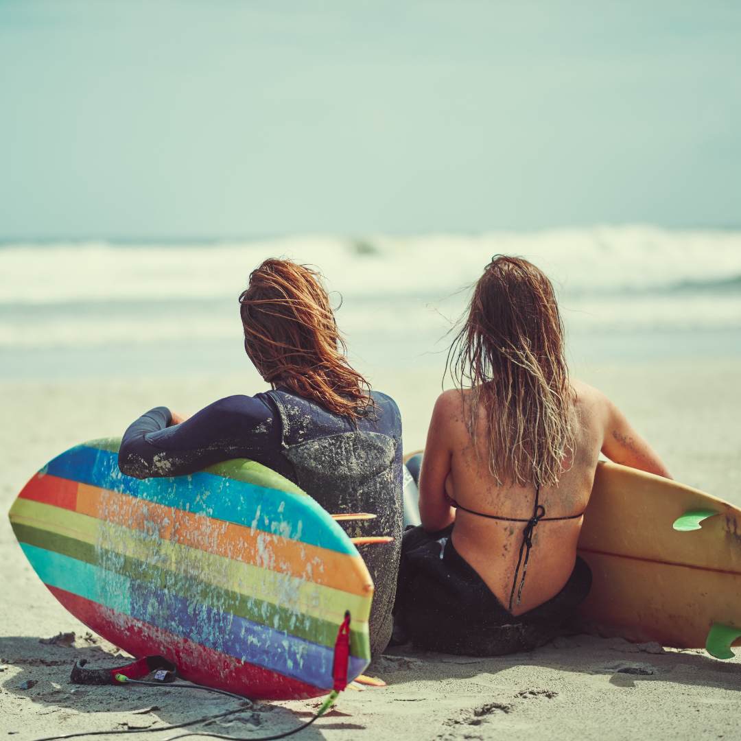 2 Frauen am Strand mit Surfbrettern
